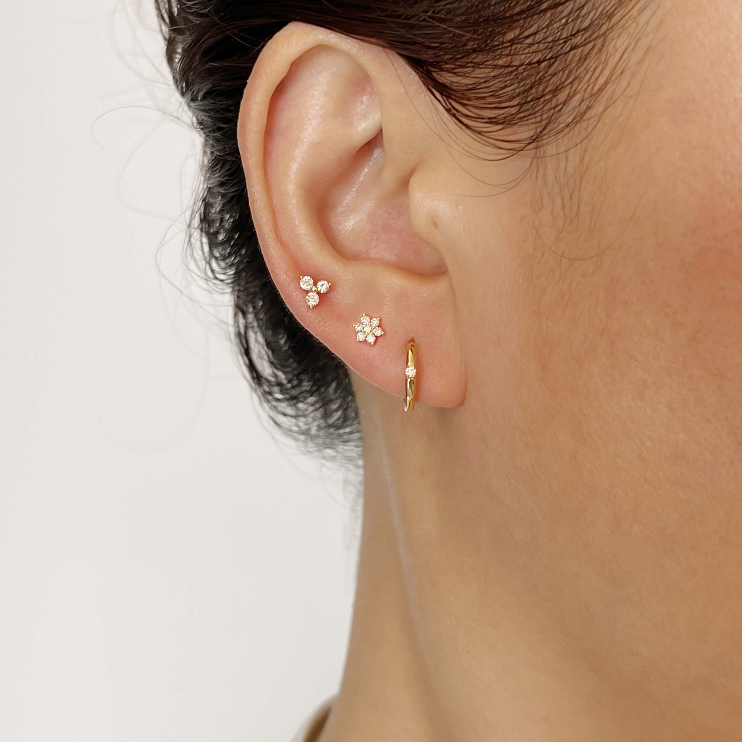 14k solid gold huggie earrings and flat-back earrings on a model